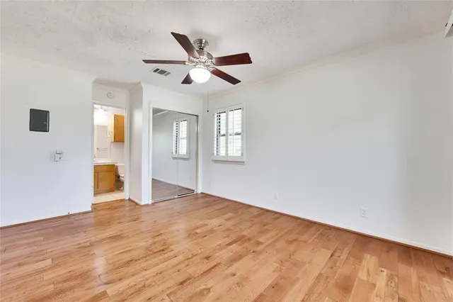 a view of empty room with wooden floor and fan