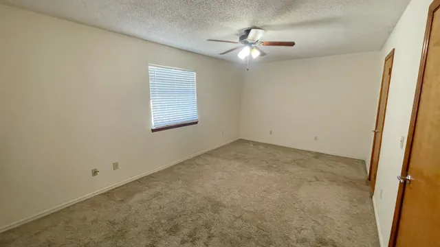 an empty room with a chandelier fan and windows