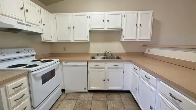 a kitchen with granite countertop white cabinets and white appliances