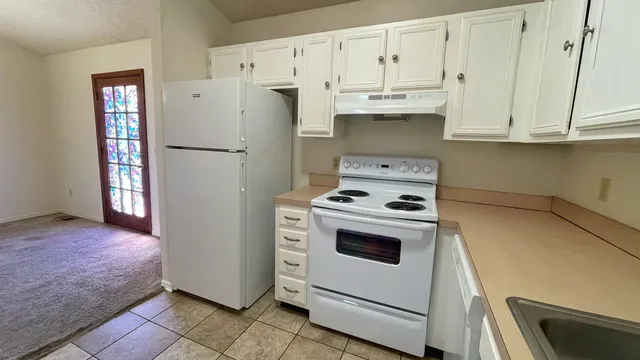 a kitchen with white cabinets and white appliances
