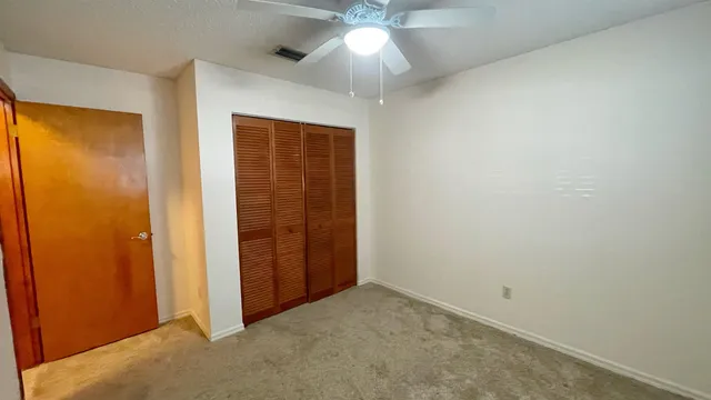 an empty room with closet and a chandelier fan