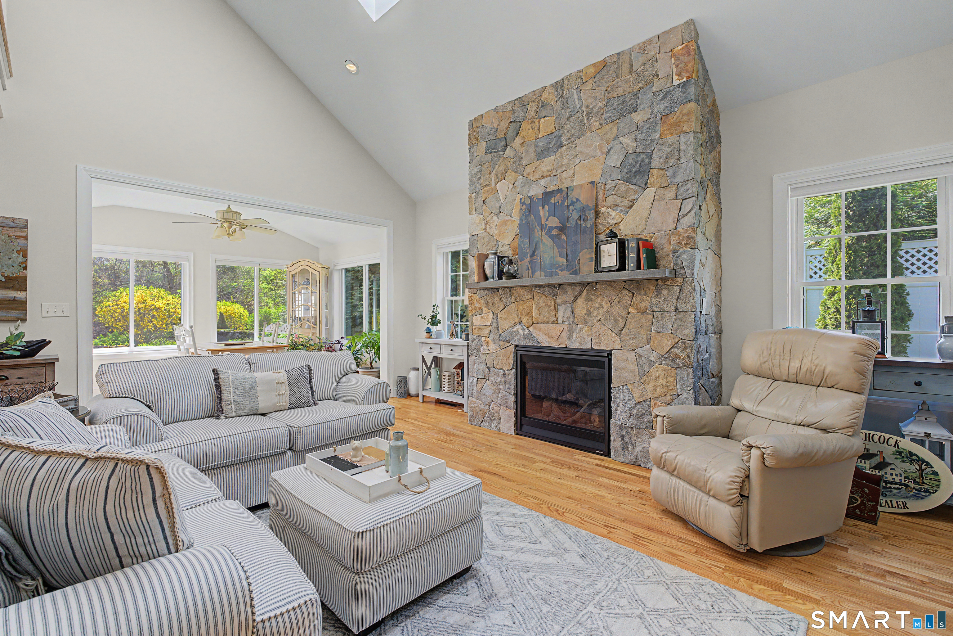 211 Meadowbrook Road, Unit 211 Oxford, CT 06478 - Photo 4 of 38 Bright and airy family room featuring soaring ceilings, abundant natural light, and a stunning floor-to-ceiling stone fireplace as the focal point.