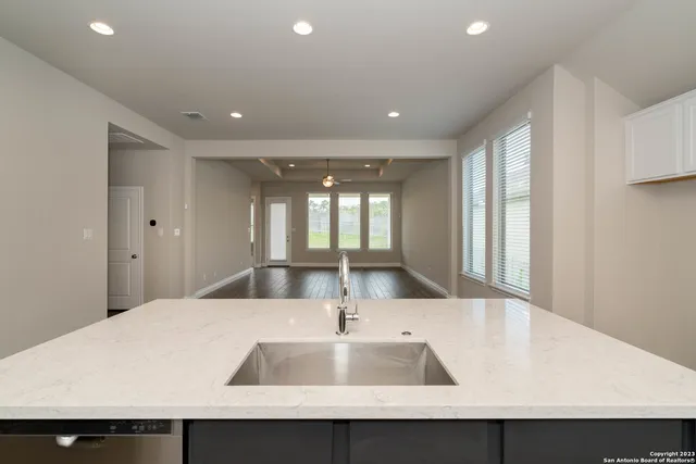 a large kitchen with stainless steel appliances a large counter top and wooden floor