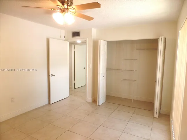 an empty room with closet and a chandelier fan