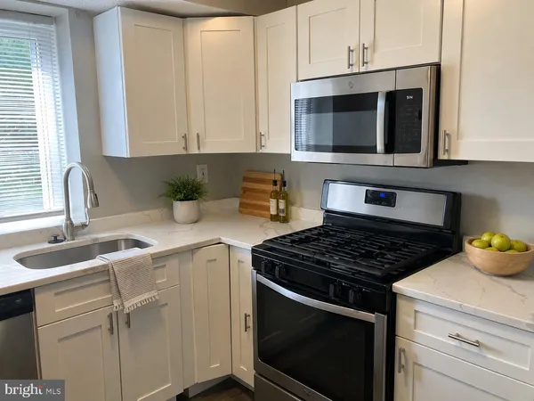 a kitchen with stainless steel appliances granite countertop white cabinets a microwave oven and a sink