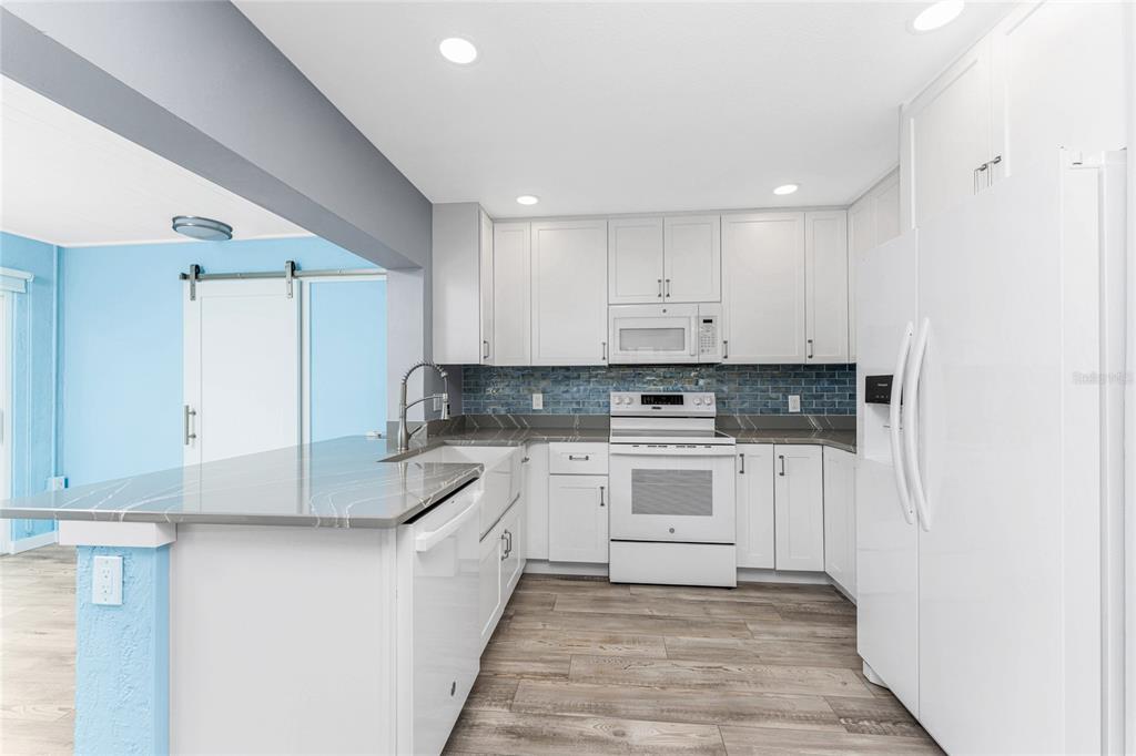 1977 Beach Road, Unit 3 Englewood, FL 34223 - Photo 6 of 56 a kitchen with granite countertop white cabinets and white appliances