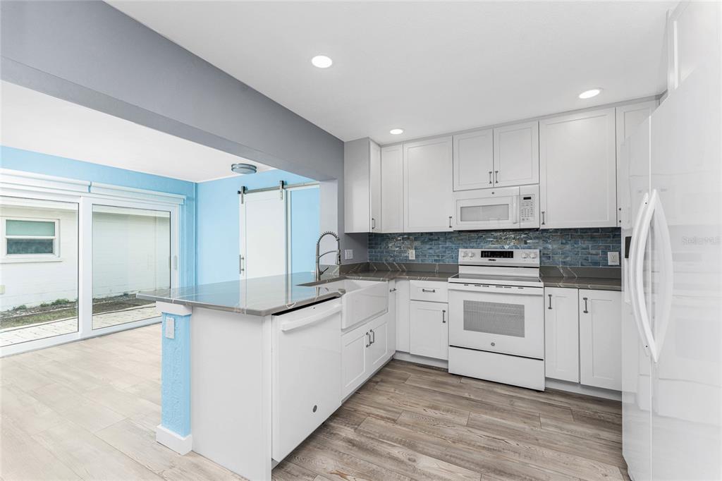 1977 Beach Road, Unit 3 Englewood, FL 34223 - Photo 7 of 56 a kitchen with granite countertop white cabinets and white appliances