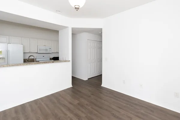 a kitchen with wooden floor and white stainless steel appliances
