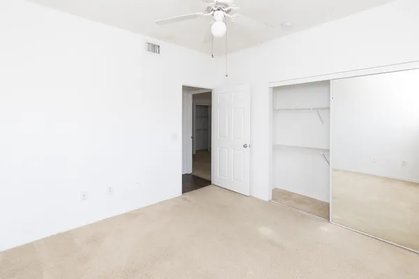 an empty room with a ceiling fan and carpet