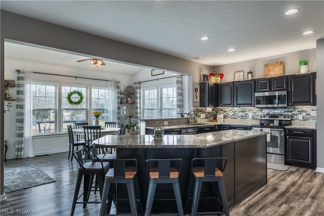 6687 List Street Northwest Canton, OH 44708 - Photo 7 of 21 Kitchen with stainless steel appliances, a center island, a breakfast bar, dark stone counters, and dark cabinetry