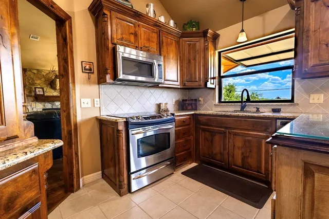 a kitchen with stainless steel appliances granite countertop a stove microwave and sink