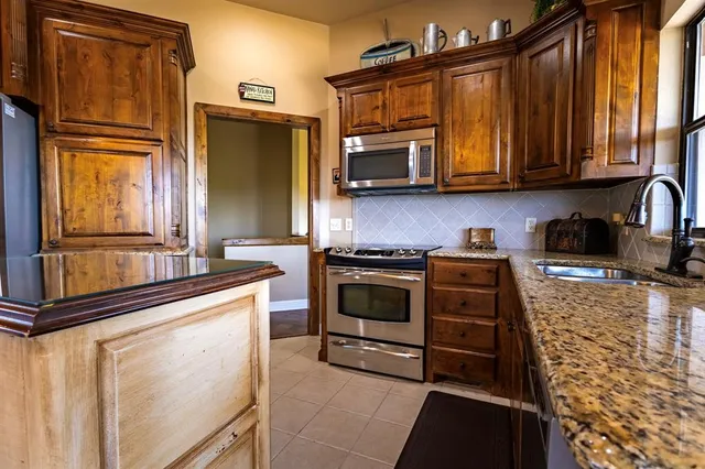 a kitchen with stainless steel appliances granite countertop a refrigerator stove and sink