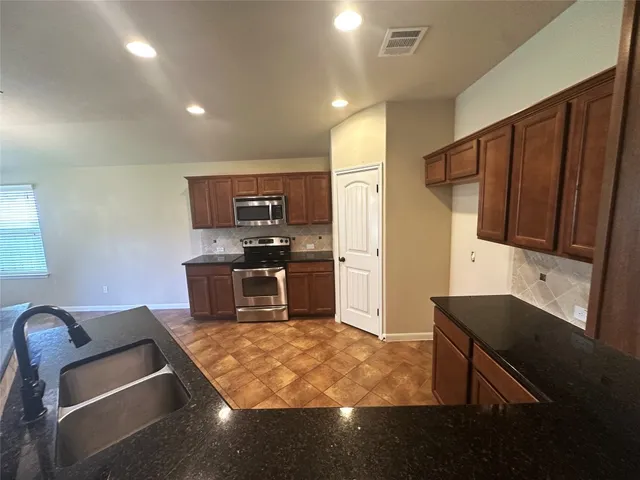 a kitchen with granite countertop a refrigerator stove and sink