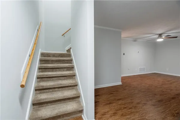 a view of an empty room with wooden floor and stairs