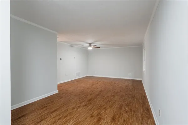 an empty room with wooden floor and fan