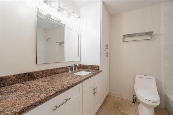 a bathroom with a granite countertop sink a toilet and a mirror