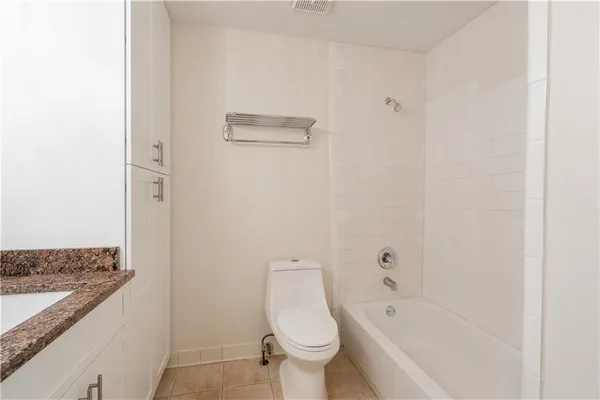 a bathroom with a granite countertop toilet and a bathtub