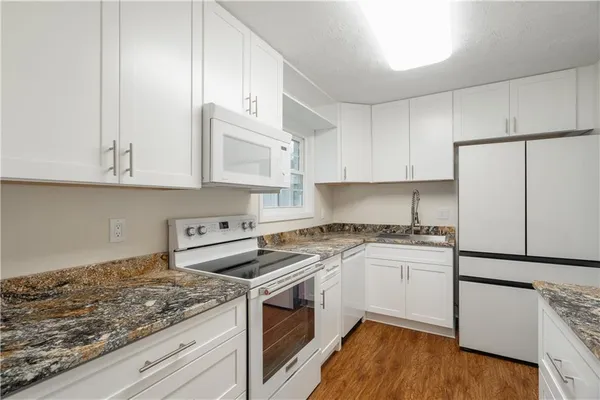 a kitchen with granite countertop white cabinets and white appliances