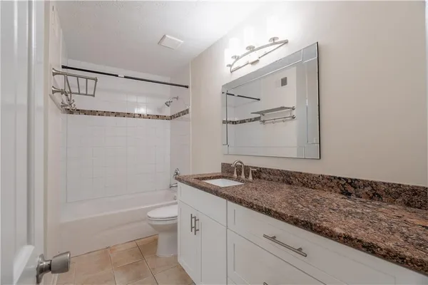 a bathroom with a granite countertop sink mirror toilet and bathtub