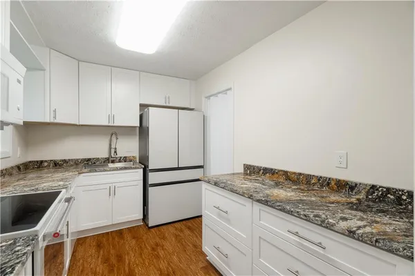 a kitchen with granite countertop white cabinets and white appliances
