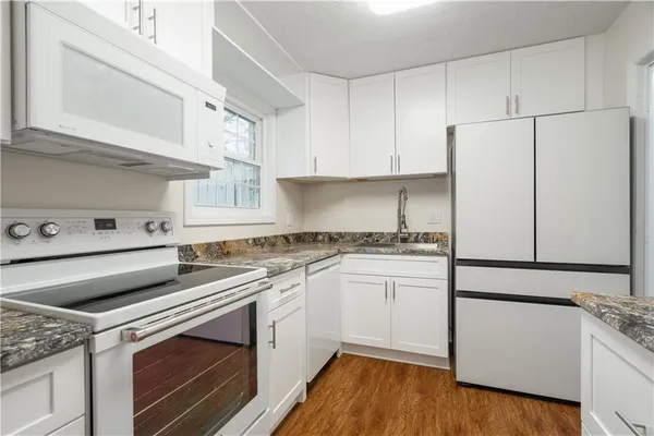 a kitchen with cabinets appliances and wooden floor