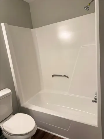 a white toilet sitting next to a bath tub