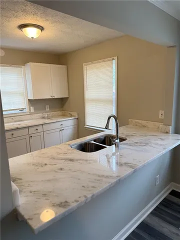 a kitchen with granite countertop a sink a stove and cabinets
