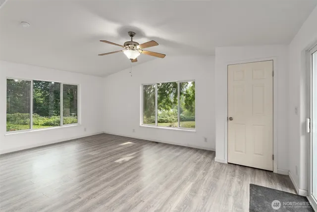 a view of empty room with wooden floor and fan