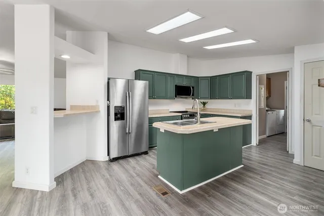 a kitchen with kitchen island a sink appliances and cabinets