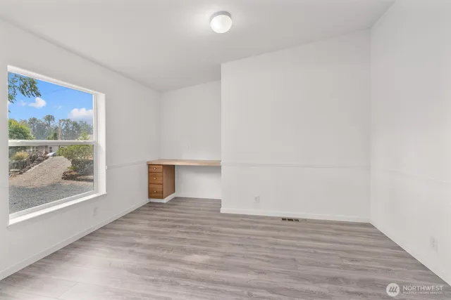 a view of empty room with wooden floor and fan