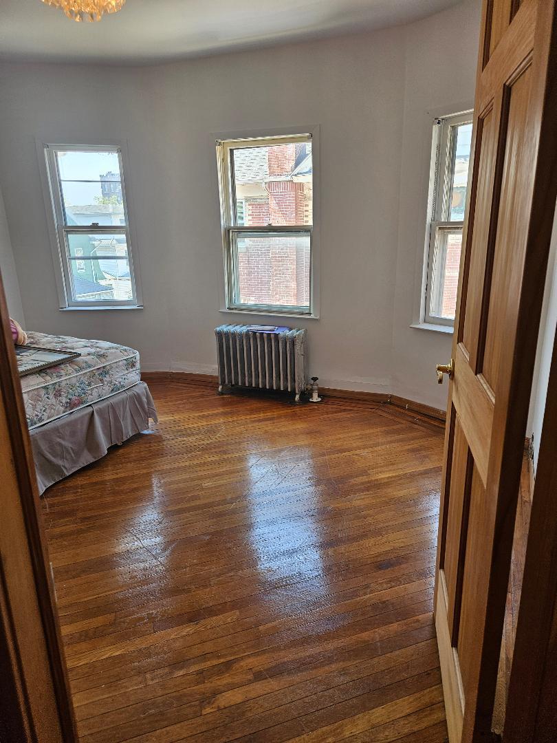 84-24 85th Road Queens, NY 11421 - Photo 6 of 10 a view of an empty room with wooden floor and a window