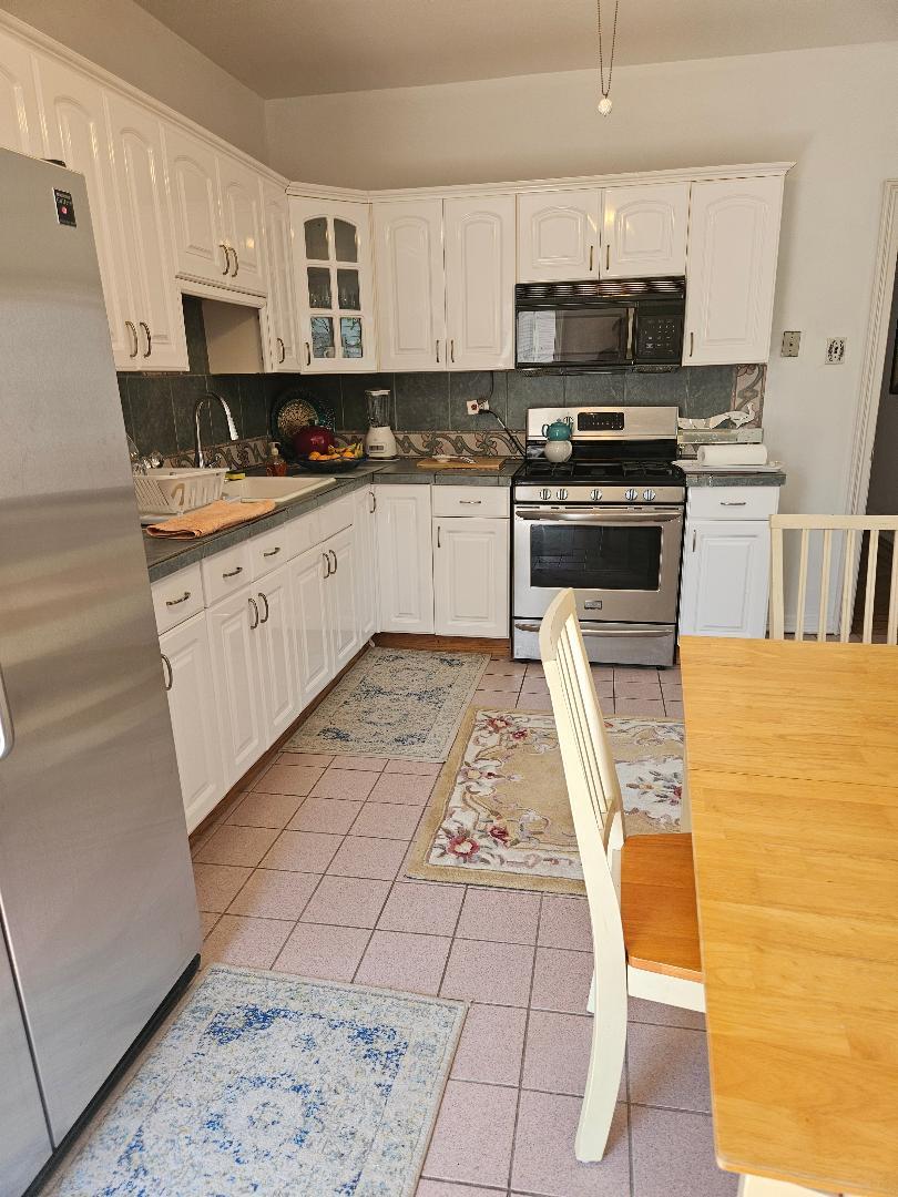 84-24 85th Road Queens, NY 11421 - Photo 7 of 10 a kitchen with stainless steel appliances a stove a sink a microwave a refrigerator and cabinets