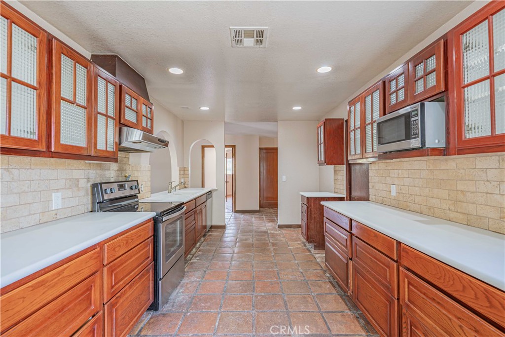 48703 De Luz Road Temecula, CA 92590 - Photo 15 of 36 a large kitchen with stainless steel appliances granite countertop a large stove top oven a sink dishwasher and a refrigerator