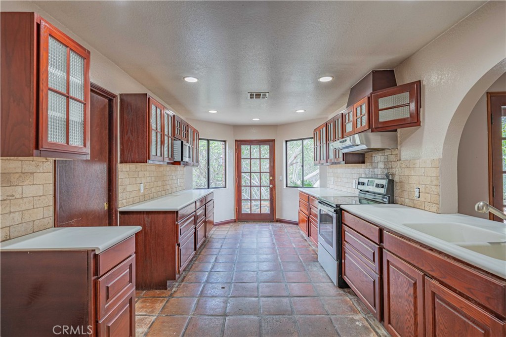48703 De Luz Road Temecula, CA 92590 - Photo 16 of 36 a large kitchen with stainless steel appliances granite countertop a large stove top oven a sink dishwasher and wooden cabinets