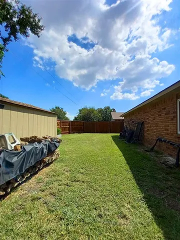 a view of a backyard with table and chairs and potted plants and large tree