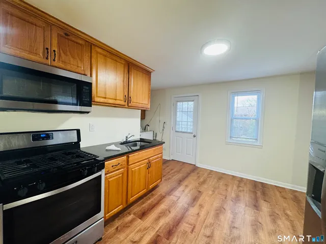 a kitchen with granite countertop wooden cabinets stainless steel appliances and a sink