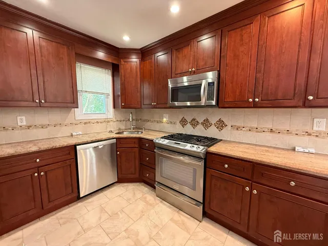 a kitchen with stainless steel appliances granite countertop wooden cabinets a stove top oven with a sink and dishwasher