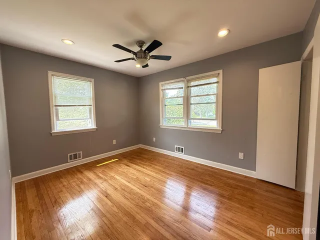 a view of an empty room with a window and wooden floor