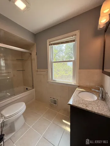 a bathroom with a granite countertop sink toilet and shower