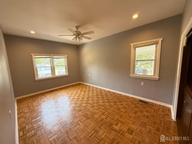 a view of empty room with wooden floor and fan