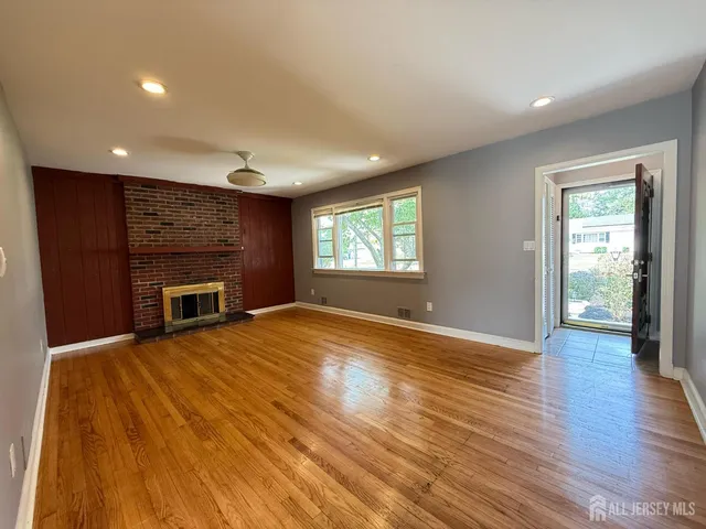 a view of empty room with wooden floor and fireplace