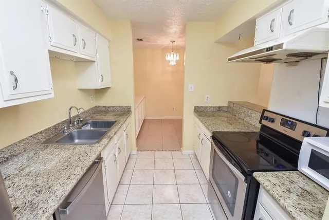 a kitchen with granite countertop a sink stove and cabinets