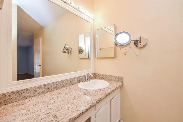 a bathroom with a granite countertop sink and a mirror