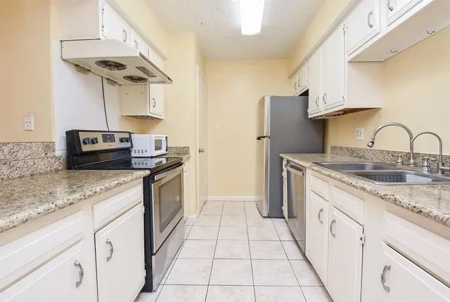a kitchen with granite countertop a sink and a stove top oven