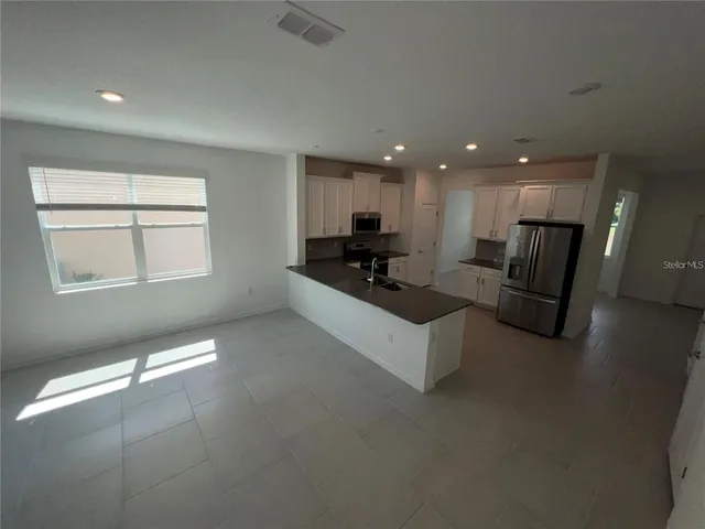 a living room with couches and kitchen view with wooden floor
