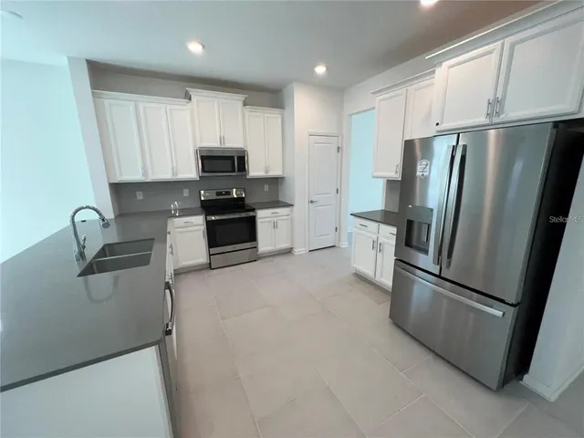 a kitchen with stainless steel appliances granite countertop a refrigerator sink and stove
