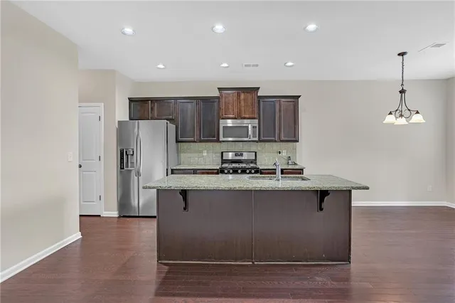 a kitchen with stainless steel appliances granite countertop a sink a stove a refrigerator and island