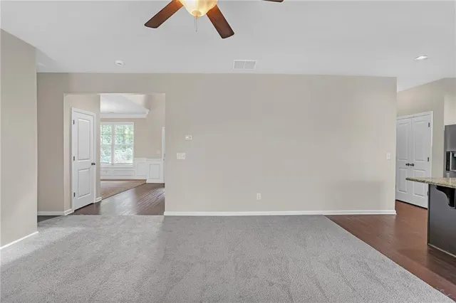 an empty room with ceiling fan and window