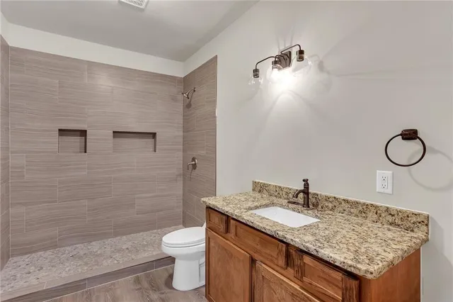 a bathroom with a granite countertop sink toilet and shower