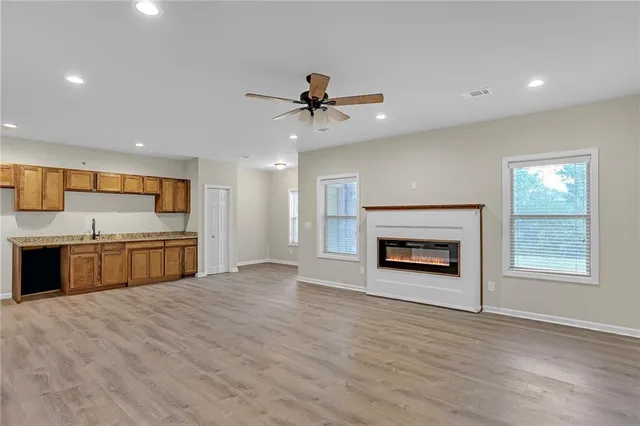 a view of an empty room with a kitchen and fireplace